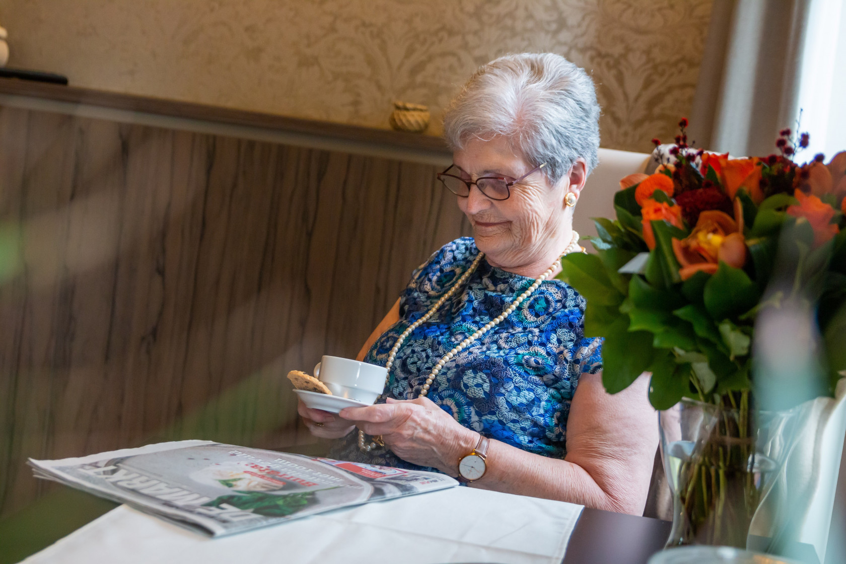 Vrouw leest krant met koffie en een koek